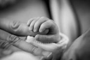 Un bébé tient la main d'un adulte.
